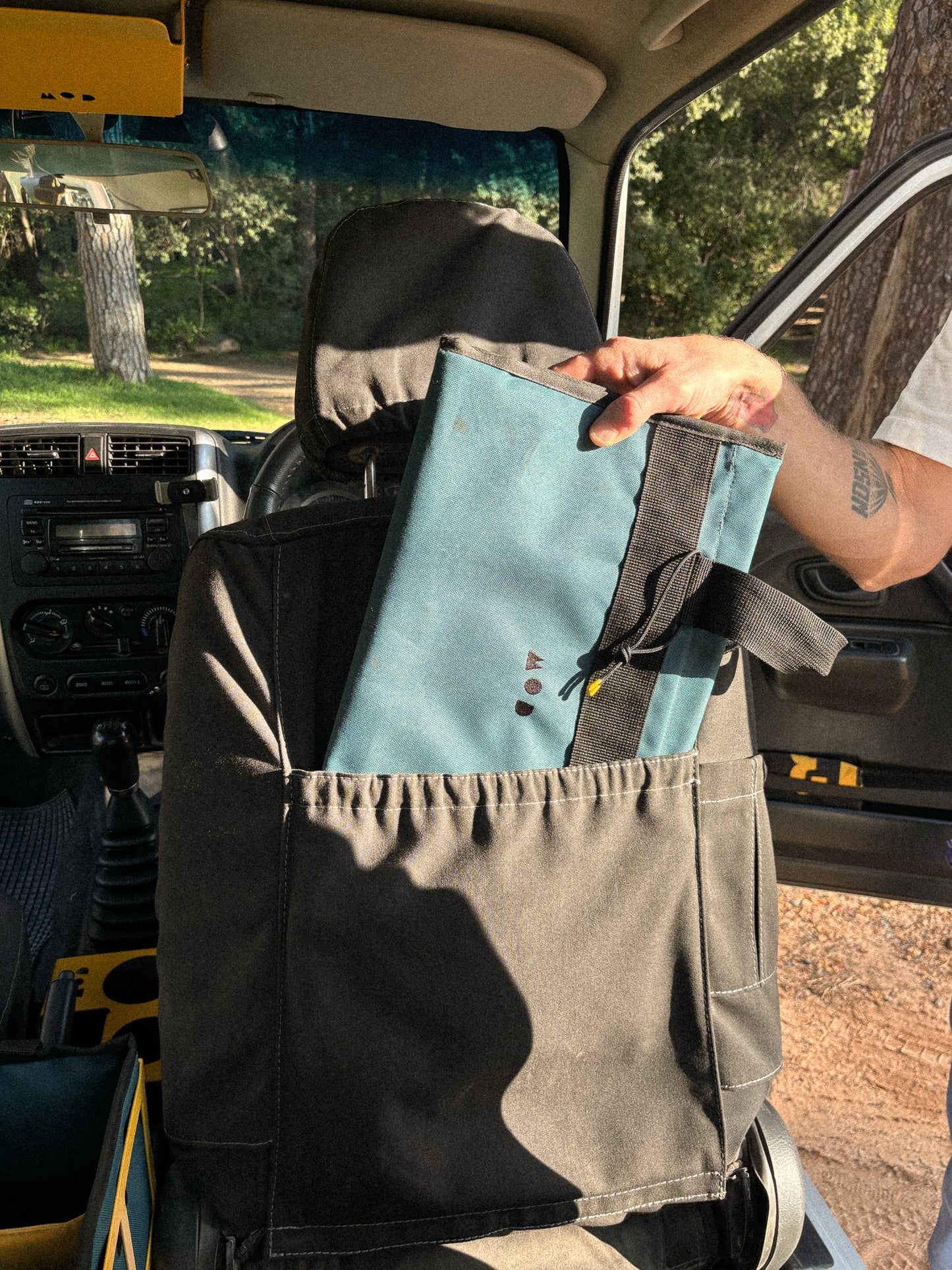 Cargo Tote in Teal, folded flat packed into the seat pouch of the Jimny